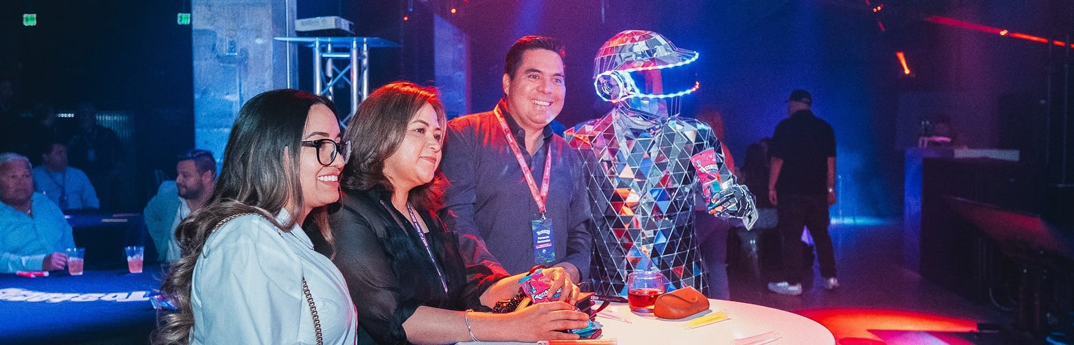 Invitados en la mesa junto a un performer con traje de espejos