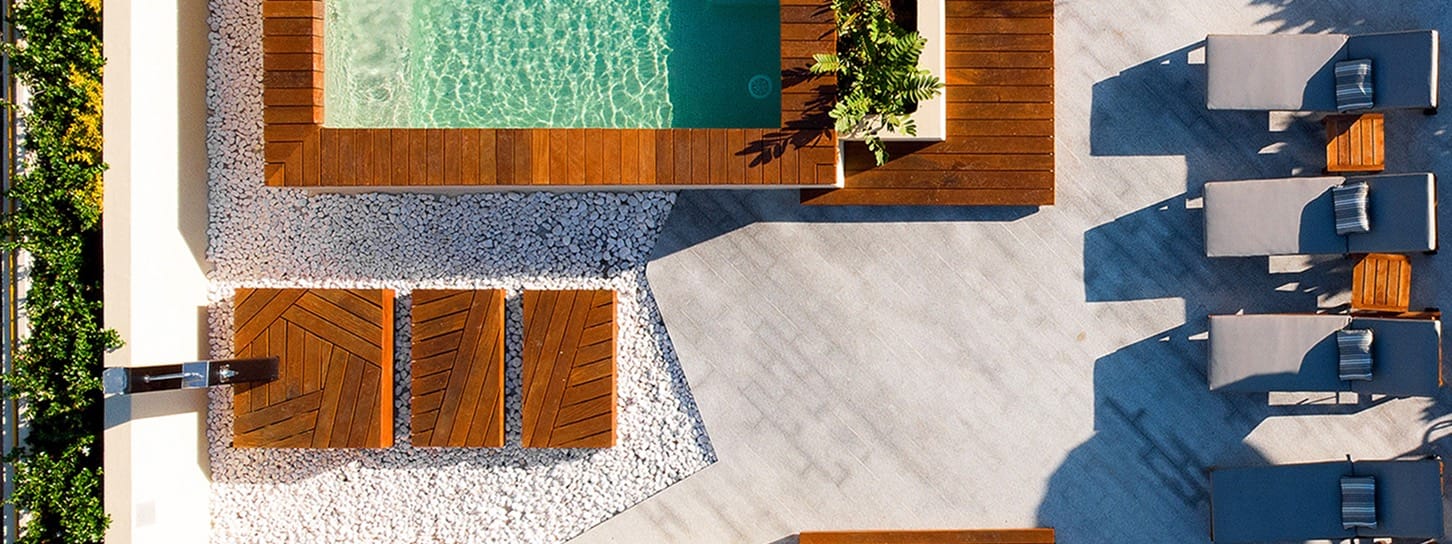 Terraza de piscina vista desde arriba, con tumbonas y vegetación