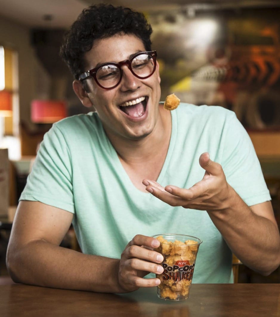 Hombre riendo con un vaso de palomitas en la mano