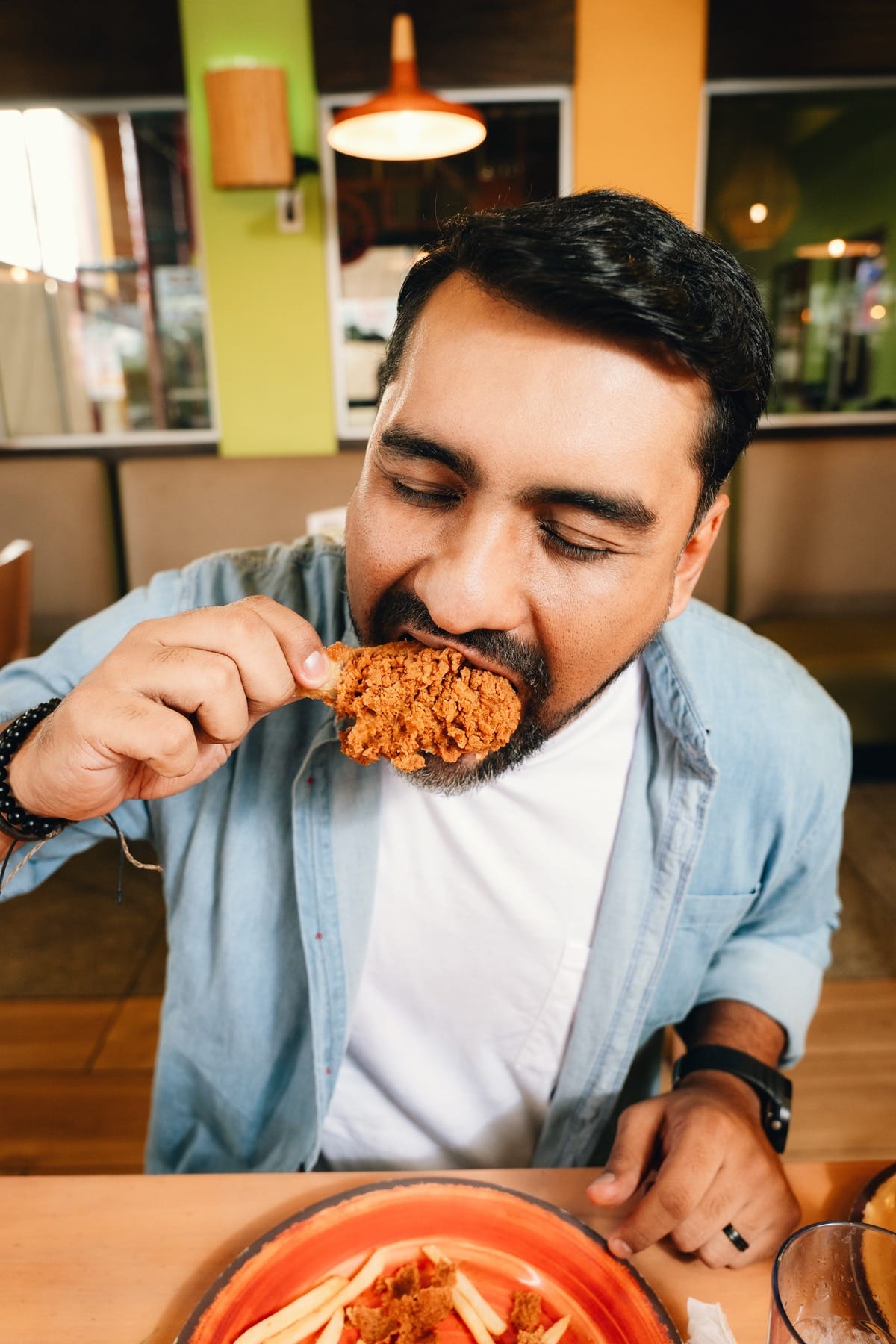 Hombre mordiendo una pieza de pollo frito