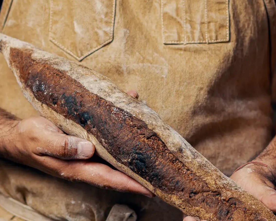 Manos sosteniendo un pan artesanal recién horneado