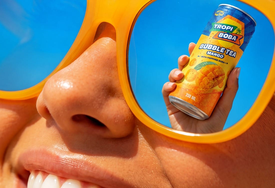 La lata reflejada en unas gafas de sol naranjas, en primer plano